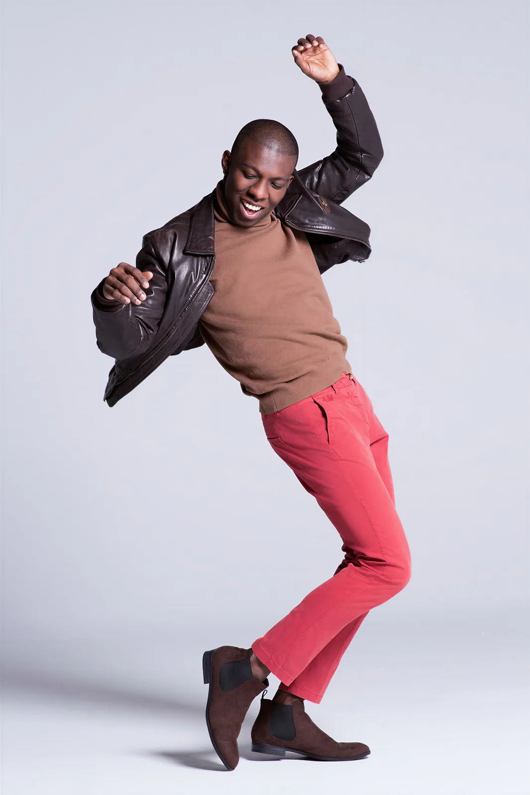 A man in red trousers caught mid-jump in the studio
