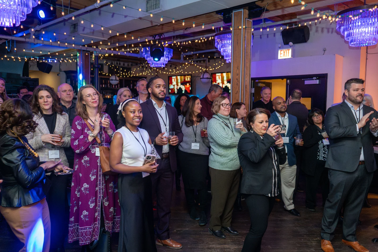 Friends applauding at a private celebration under string lights